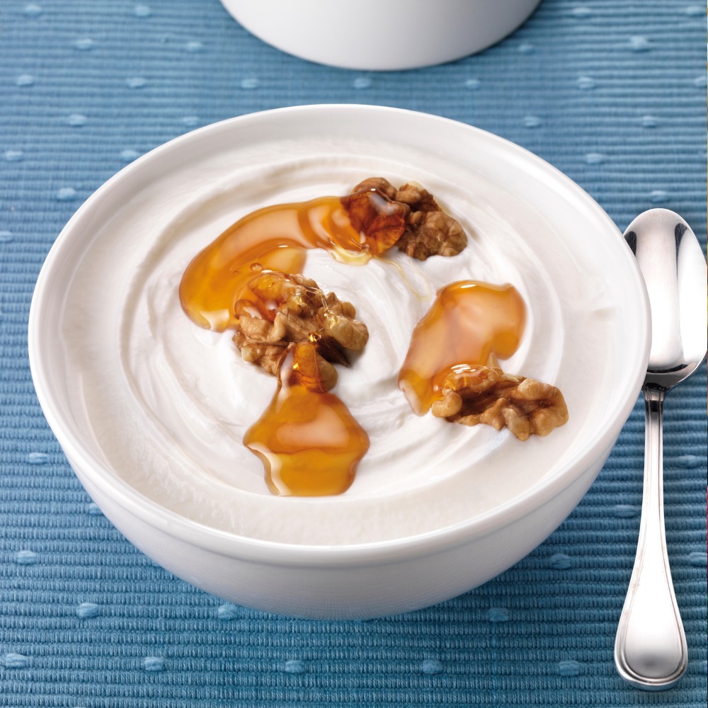  A bowl of Greek yogurt drizzled with honey and topped with chopped walnuts, served with a side of fresh berries.