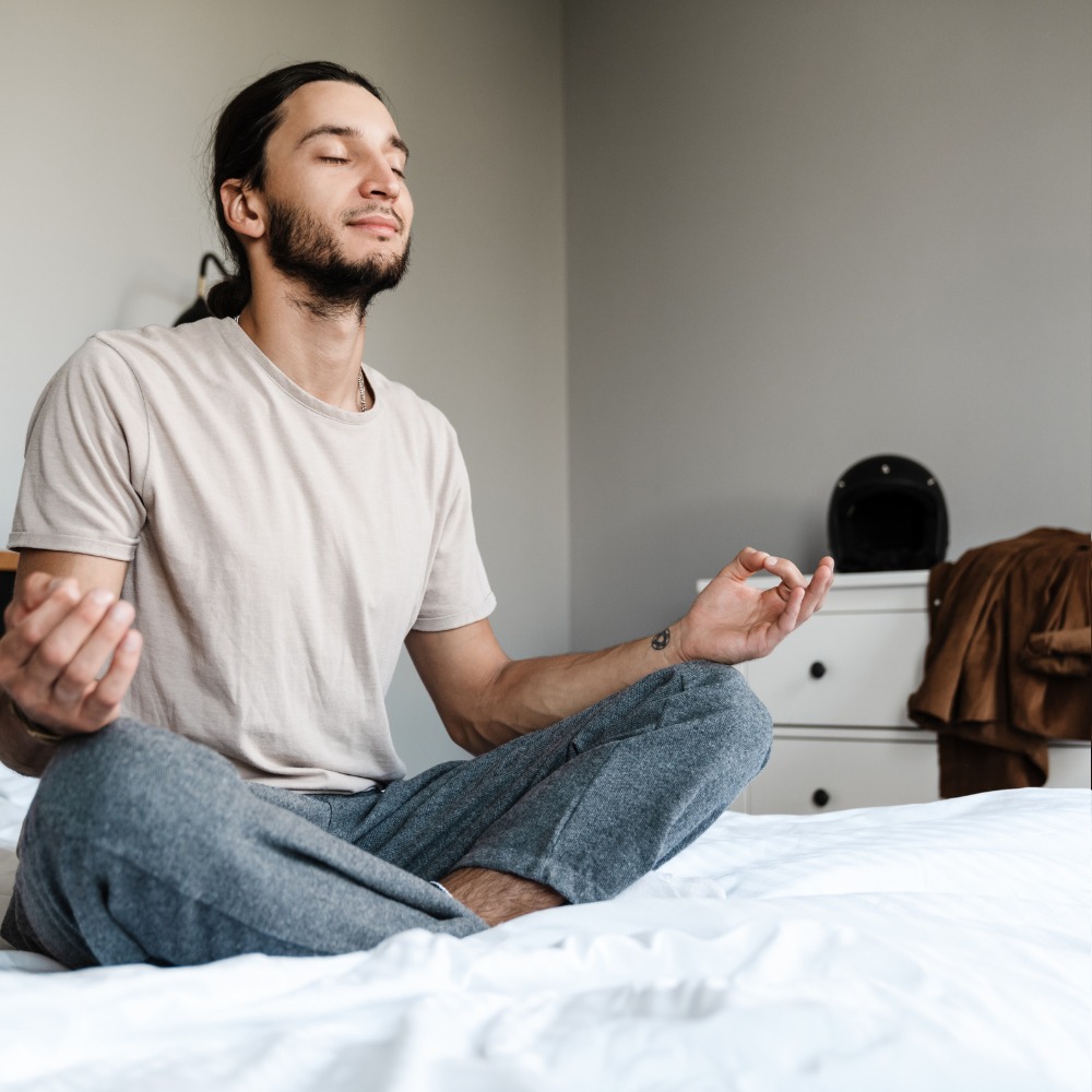  A person sitting cross-legged on a yoga mat, meditating in a peaceful, minimalist room.