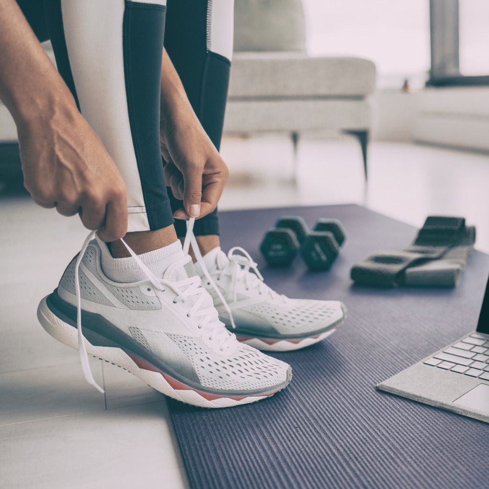 "Person tying running shoes next to fitness equipment, representing the importance of physical activity in a 30-day weight loss journey."