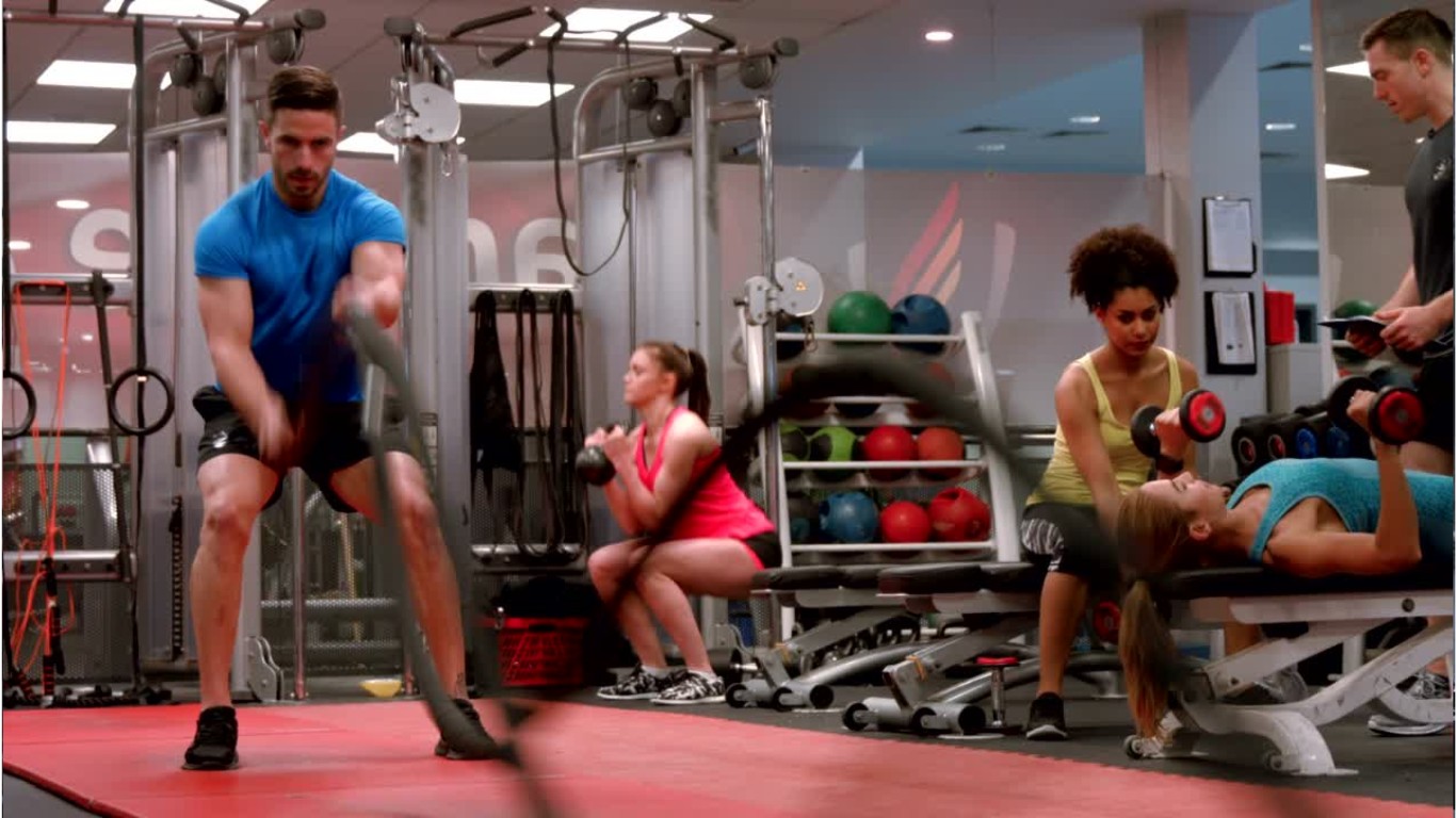 Group of individuals performing full-body toning exercises, including push-ups, squats, and kettlebell swings, in a dynamic workout environment.