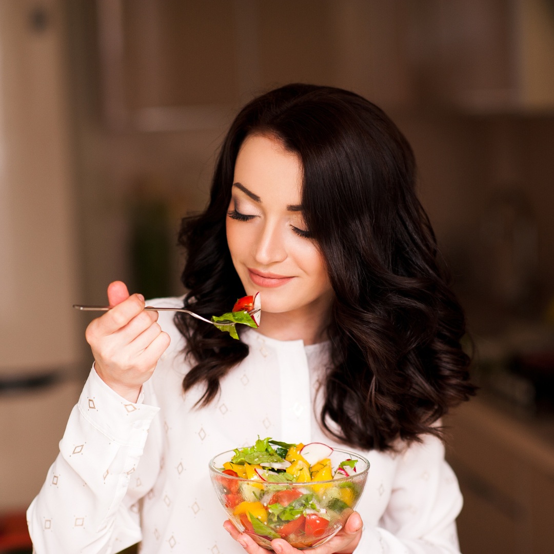 Close-up of a woman’s hands holding fresh fruits and vegetables, promoting healthy eating for aging gracefully."