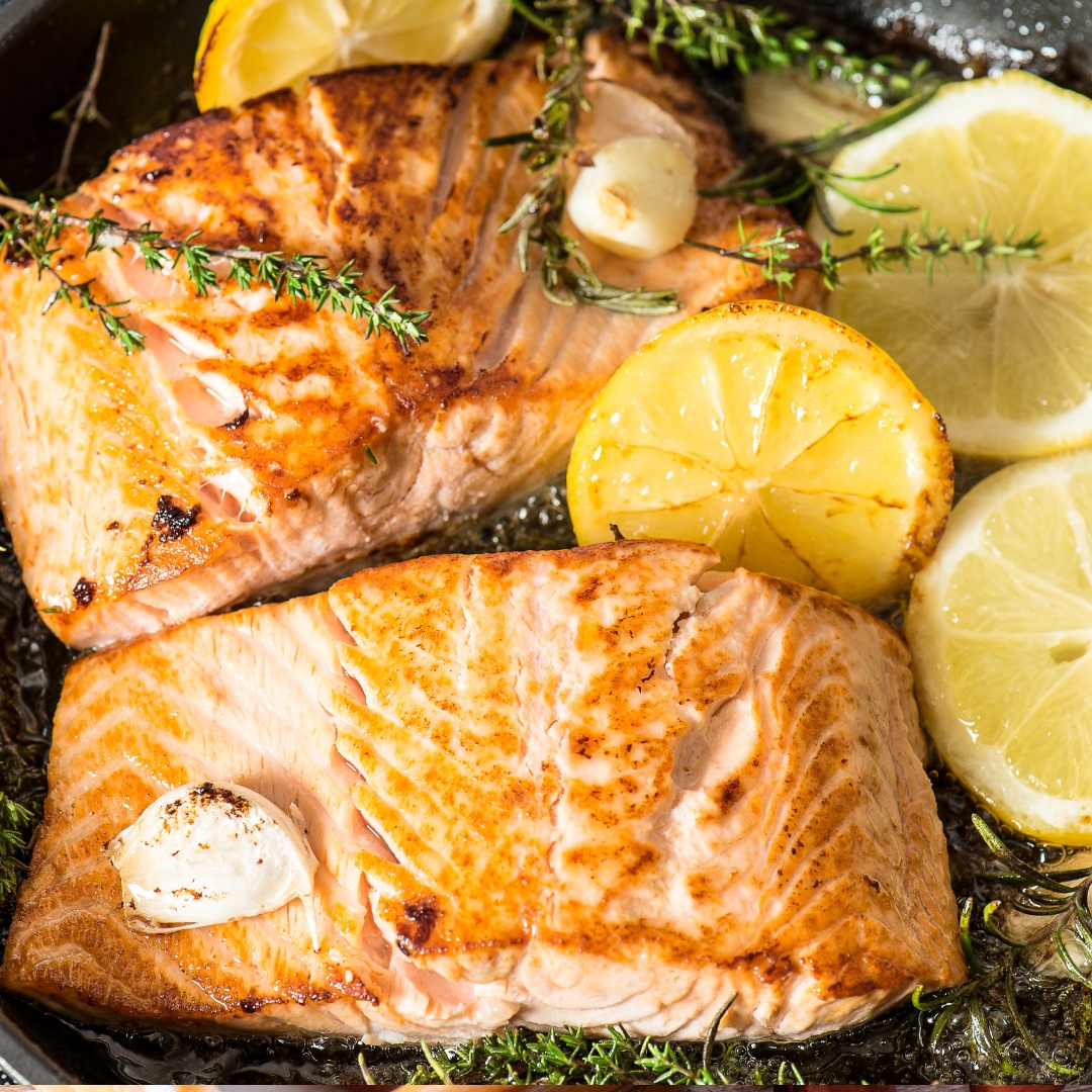 Garlic herb roasted salmon fillets garnished with fresh parsley and lemon slices on a parchment-lined baking sheet.