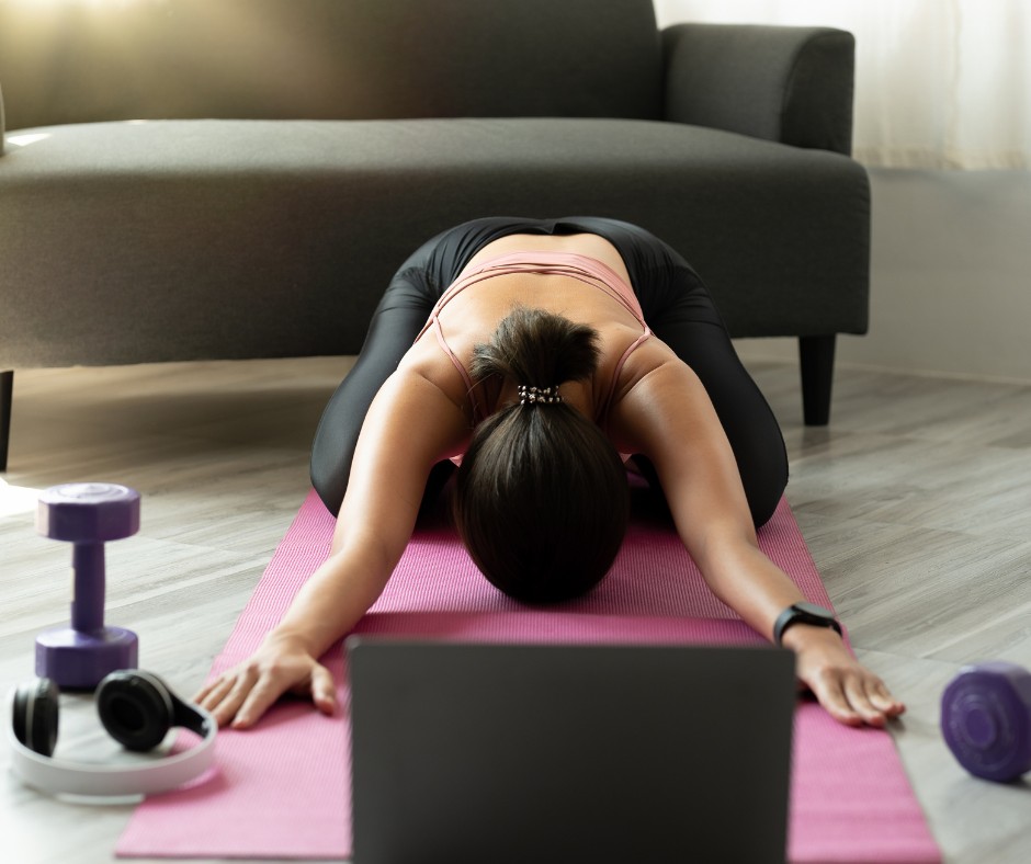 Woman practicing yoga at home with a virtual fitness class to stay motivated and active indoors during winter.