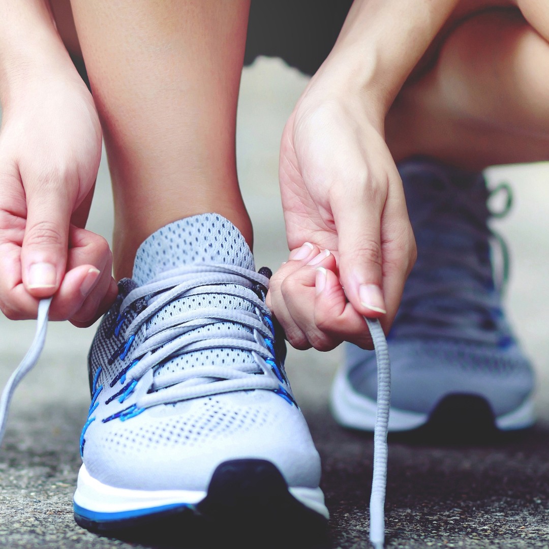 A person tying their gym shoes in a home gym, symbolizing commitment to a personalized workout plan.