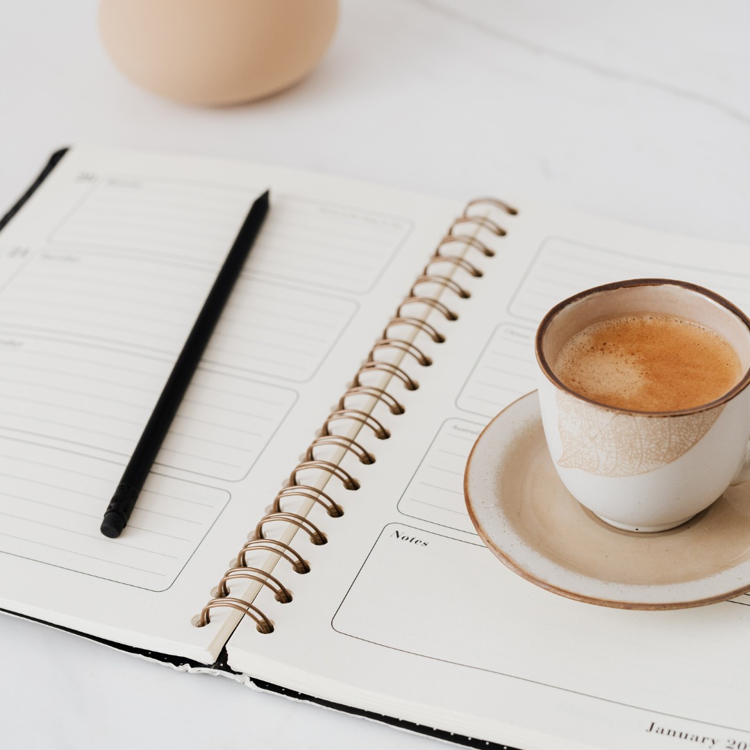 A journal with daily intentions written next to a cup of coffee, symbolizing goal setting.