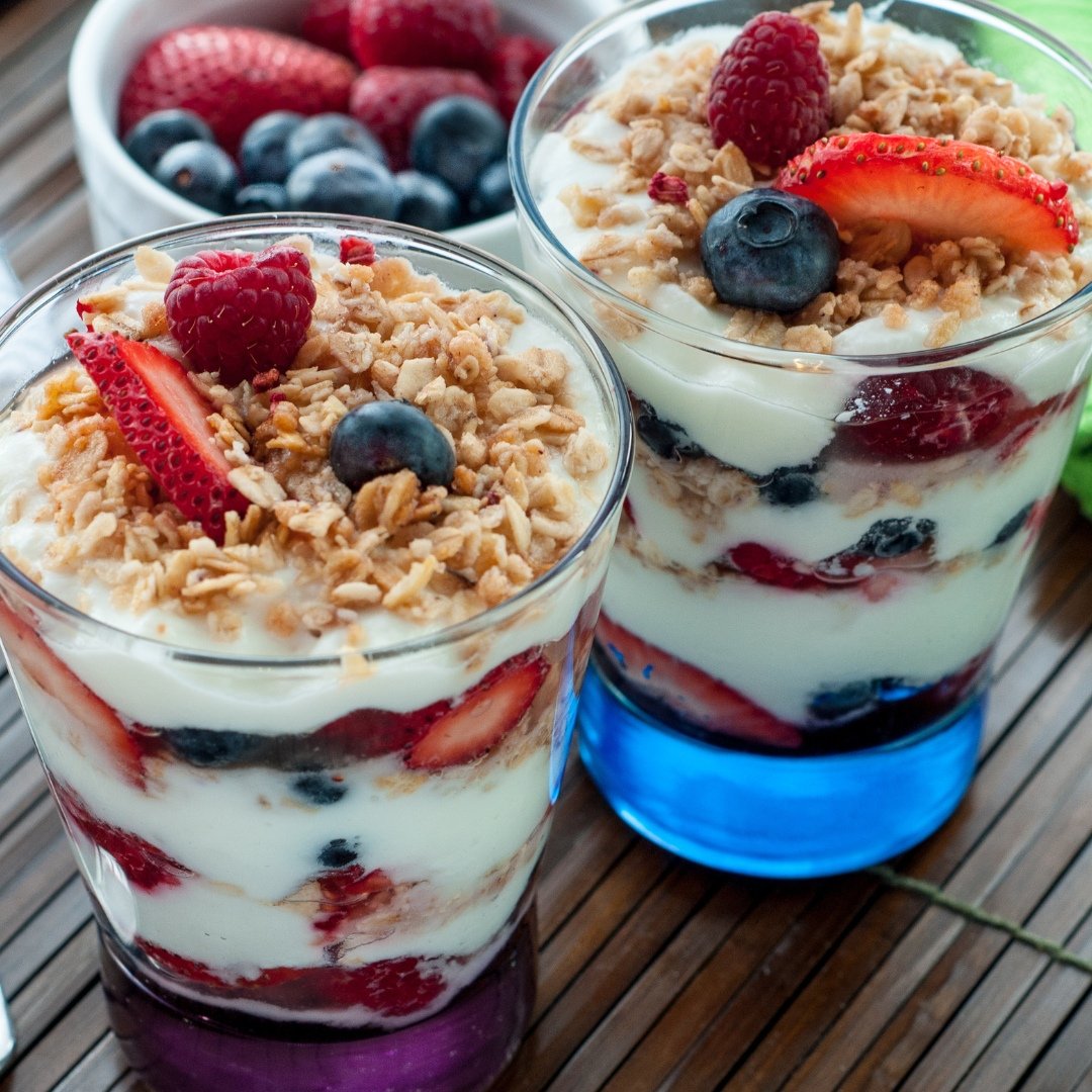  A layered parfait with Greek yogurt, mixed berries, and granola in a clear glass.