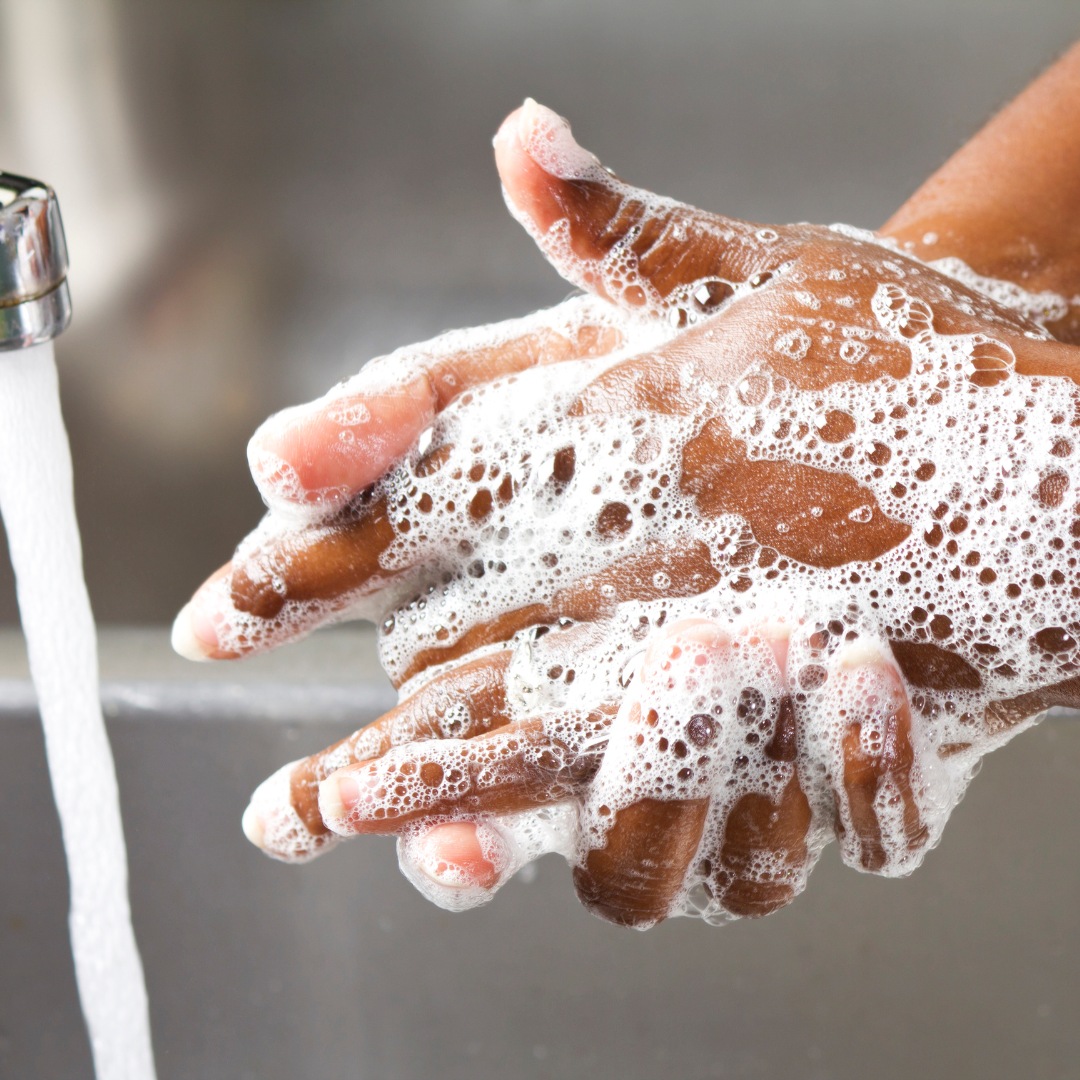 A close-up of hands being washed under running water, promoting hygiene as a key immune defense.