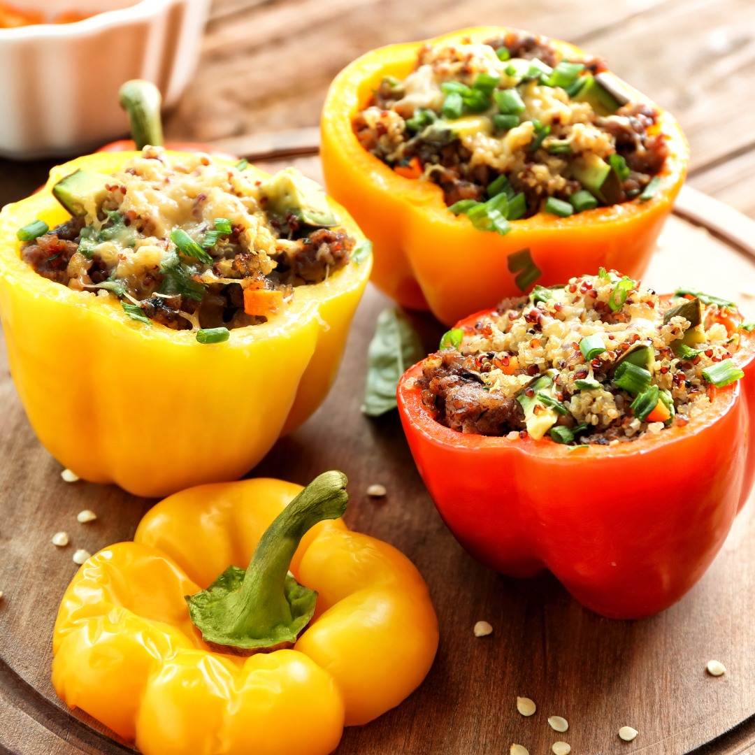 Halved bell peppers filled with a quinoa and black bean mixture, garnished with fresh herbs.