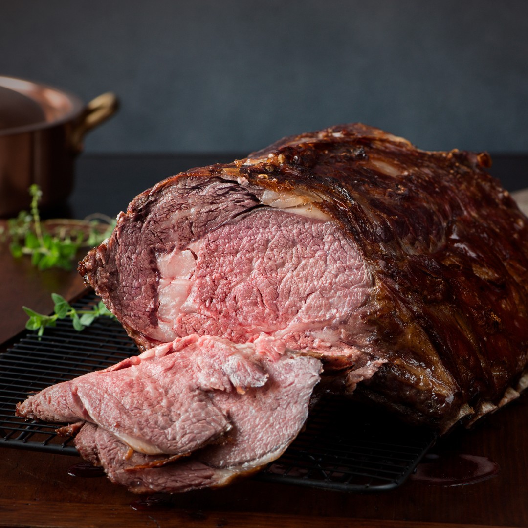 A golden-brown prime rib roast surrounded by festive garnishes, ready to be served.