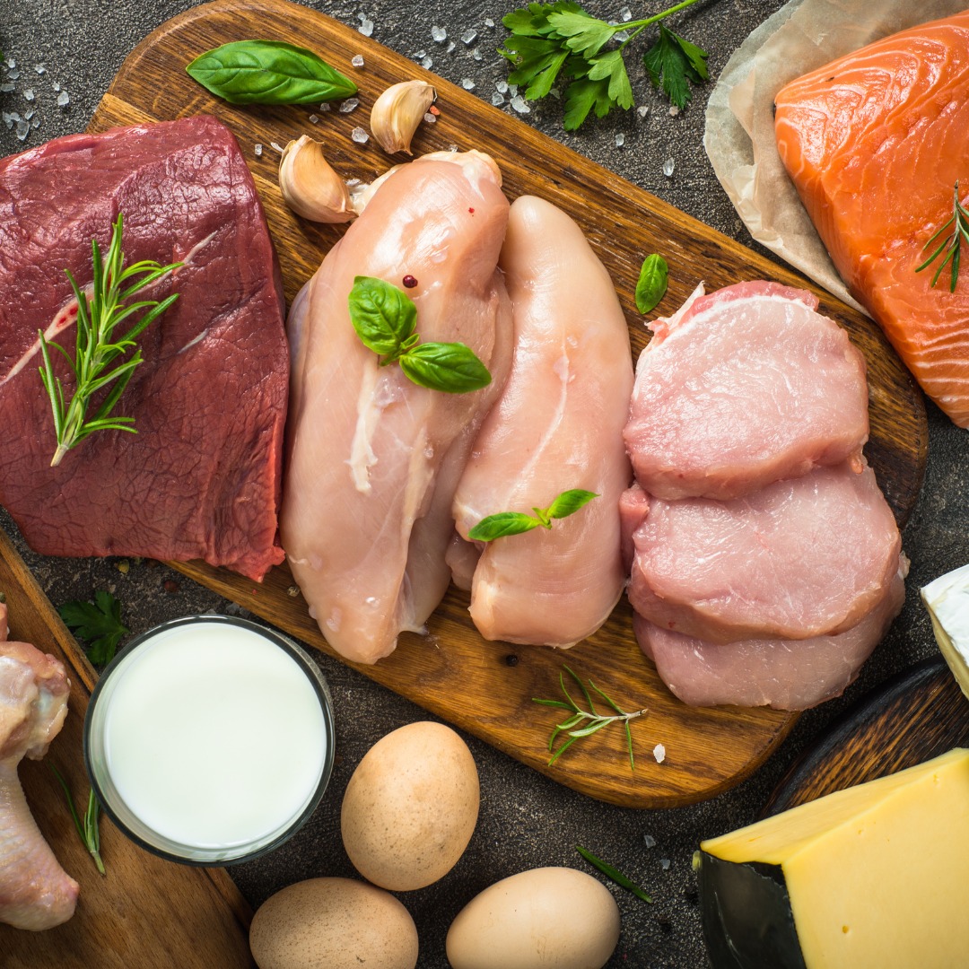 Raw protein sources, including eggs, lentils, tofu, and chicken breasts, displayed on a wooden board.