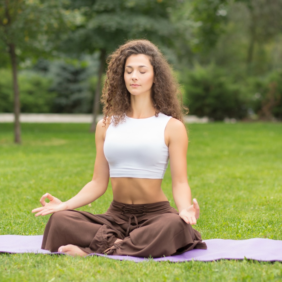 A person meditating outdoors, representing stress reduction and mindfulness. Individual meditating outdoors, practicing stress-reducing habits for mental well-being.