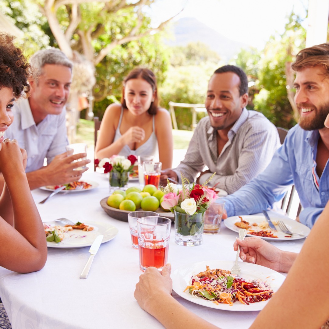 A group of friends laughing and enjoying a healthy meal together, illustrating the joy of social connections and healthy living. Friends sharing a healthy meal and laughing together.