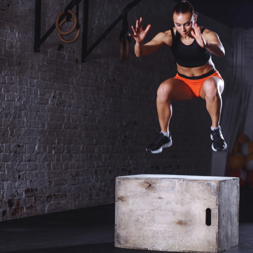 Athlete performing an explosive box jump in a gym.