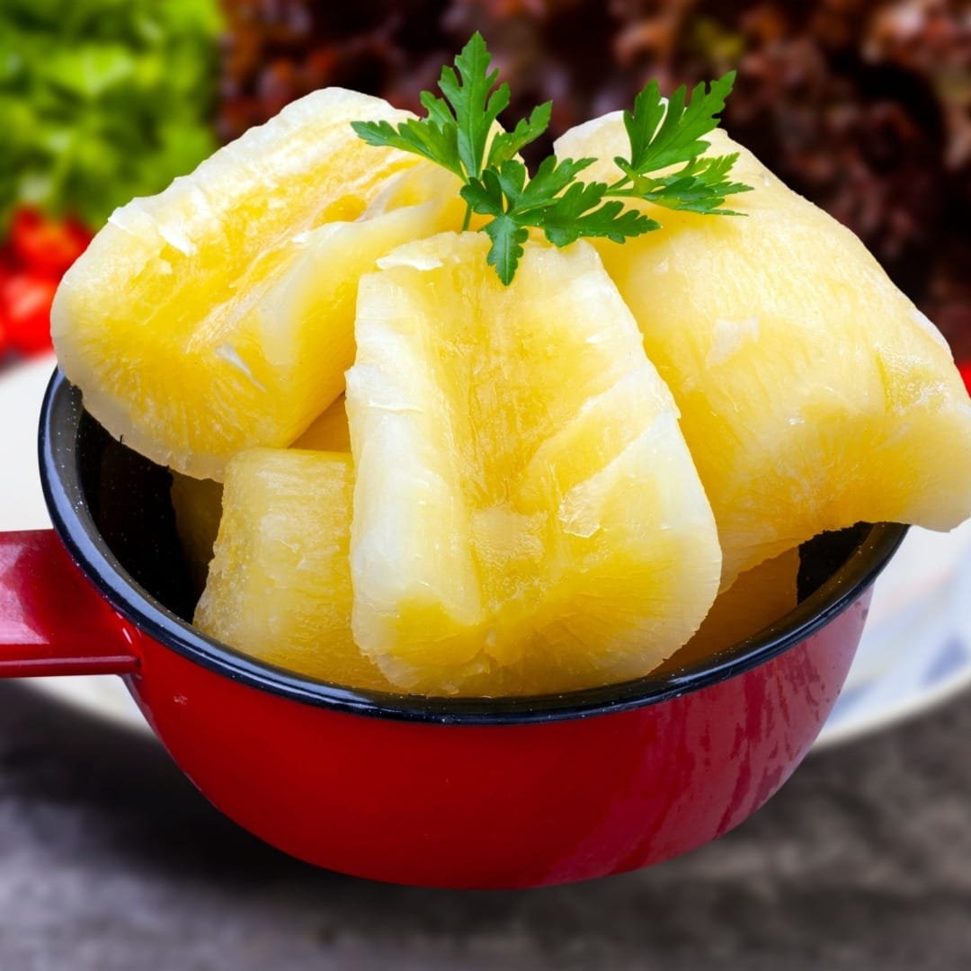 Boiled cassava chunks on a plate with coconut garnish. Traditional boiled cassava snack with grated coconut.